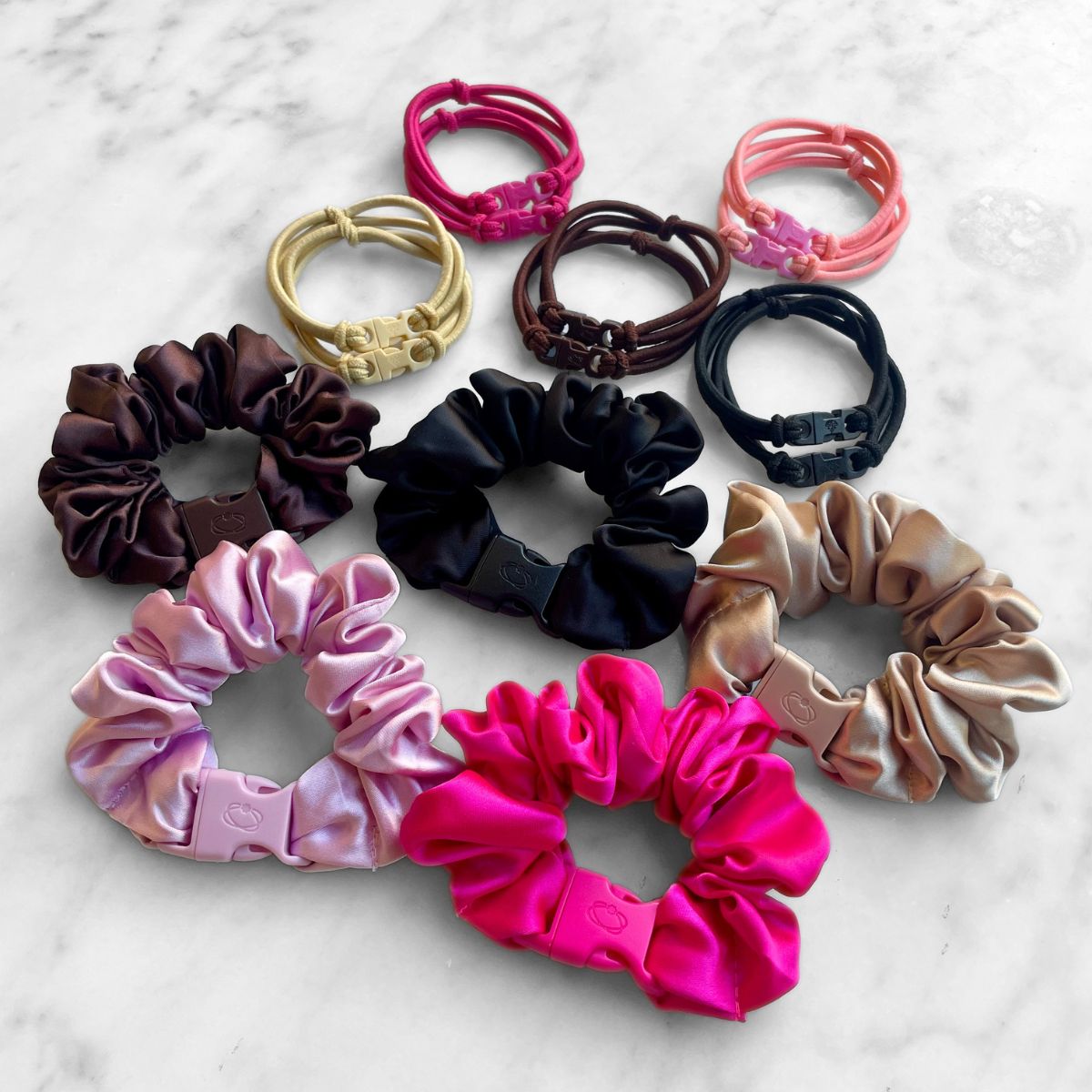 Best Sellers Gift Set: Buckle Hair Ties in pairs of Baby Pink, Hot Pink, Chocolate Brown, Industrial Black and Champagne Blonde above five satin Buckle Scrunchies