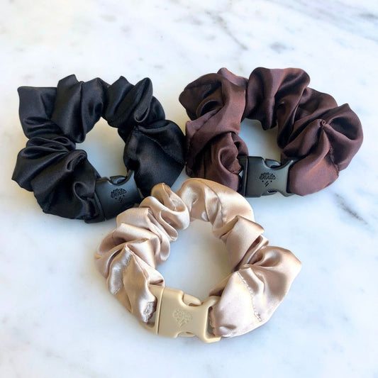 Three neutral Buckle Scrunchies in black, beige, and brown recycled satin
