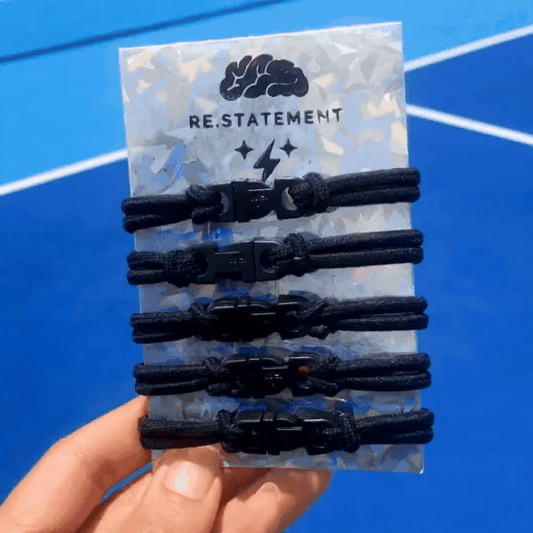 Hand holding a black Buckle Hair Tie on a blue court