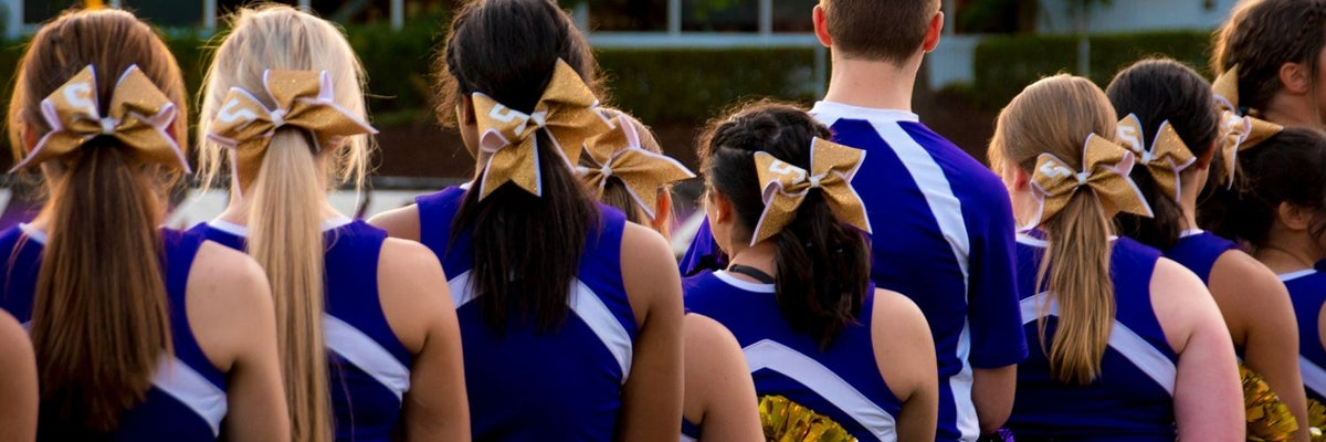 Senior night gifts: Cheer squad seen from behind in blue uniforms with bows in their ponytails