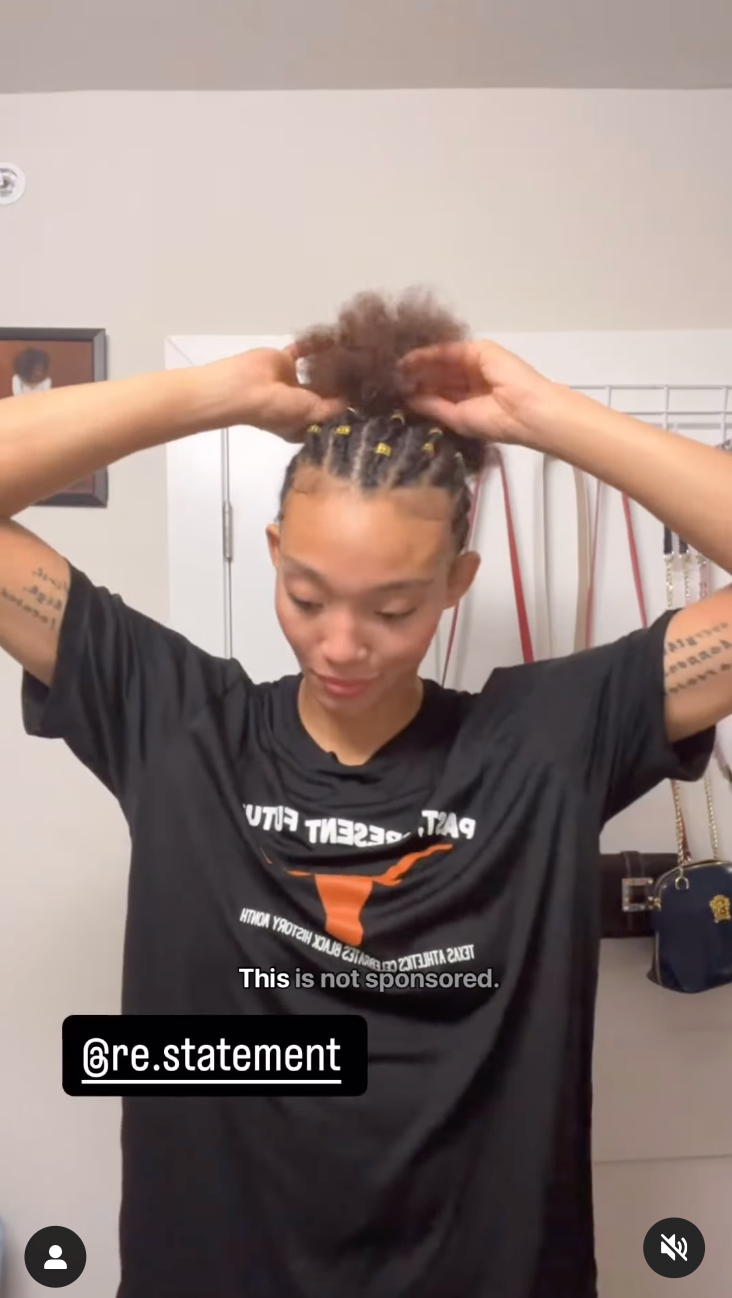 Wrestling gifts: Woman in a black tee tying her hair up in a gym mirror