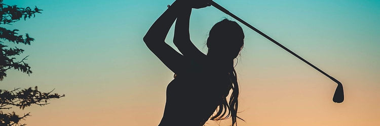 Golf accessories for women: Golfer with a ponytail at the top of her swing at sunset