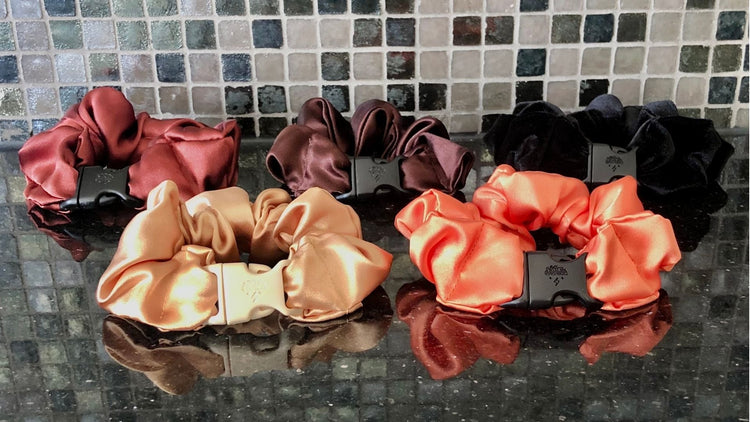 Gifts for sister: Buckle Scrunchies in coral and black satin on a mosaic tile surface