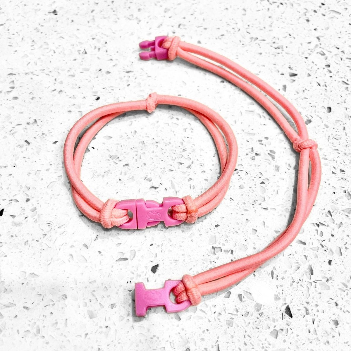 Baby Pink Buckle Hair Tie elastic clasped in a loop beside an open one showing the pink quick release buckle
