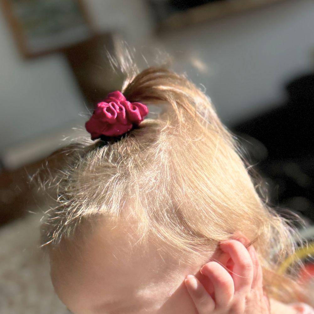 Toddler wearing a BABY Buckle Scrunchie in a small ponytail