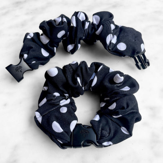 Black and white polka dot Buckle Scrunchie with a black quick-release buckle on marble