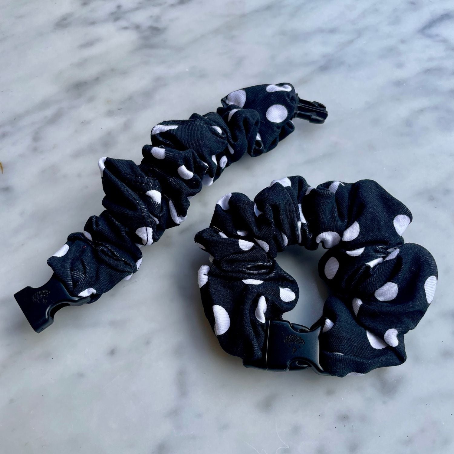 Black polka dot Buckle Scrunchie beside an open one with the buckle unclipped