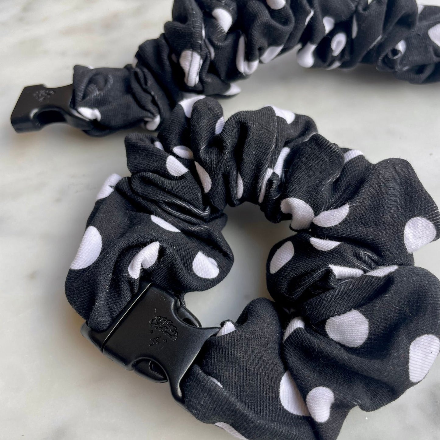 Close view of the black and white polka dot fabric on a Buckle Scrunchie