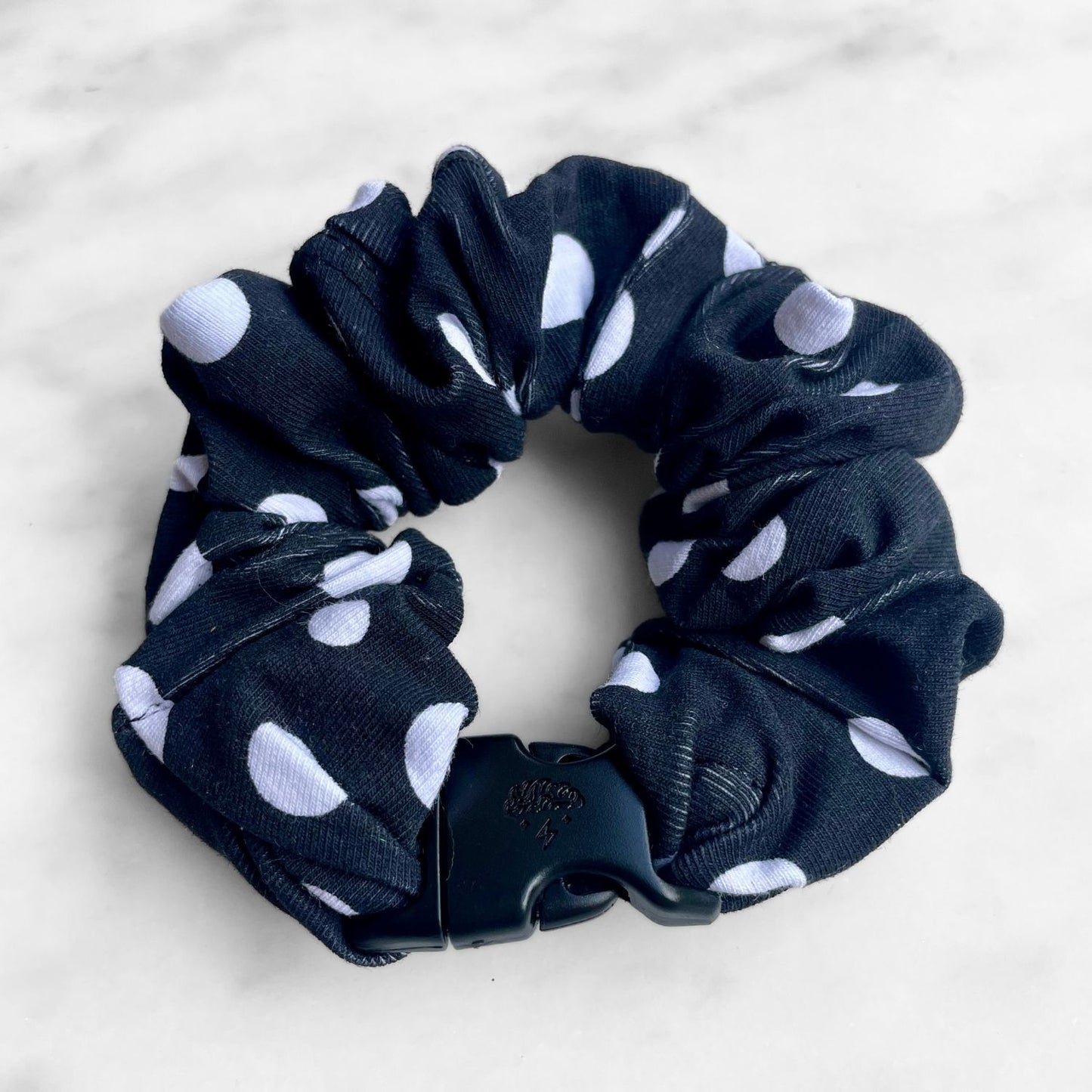 Black polka dot Buckle Scrunchie fastened in a ring with its black buckle