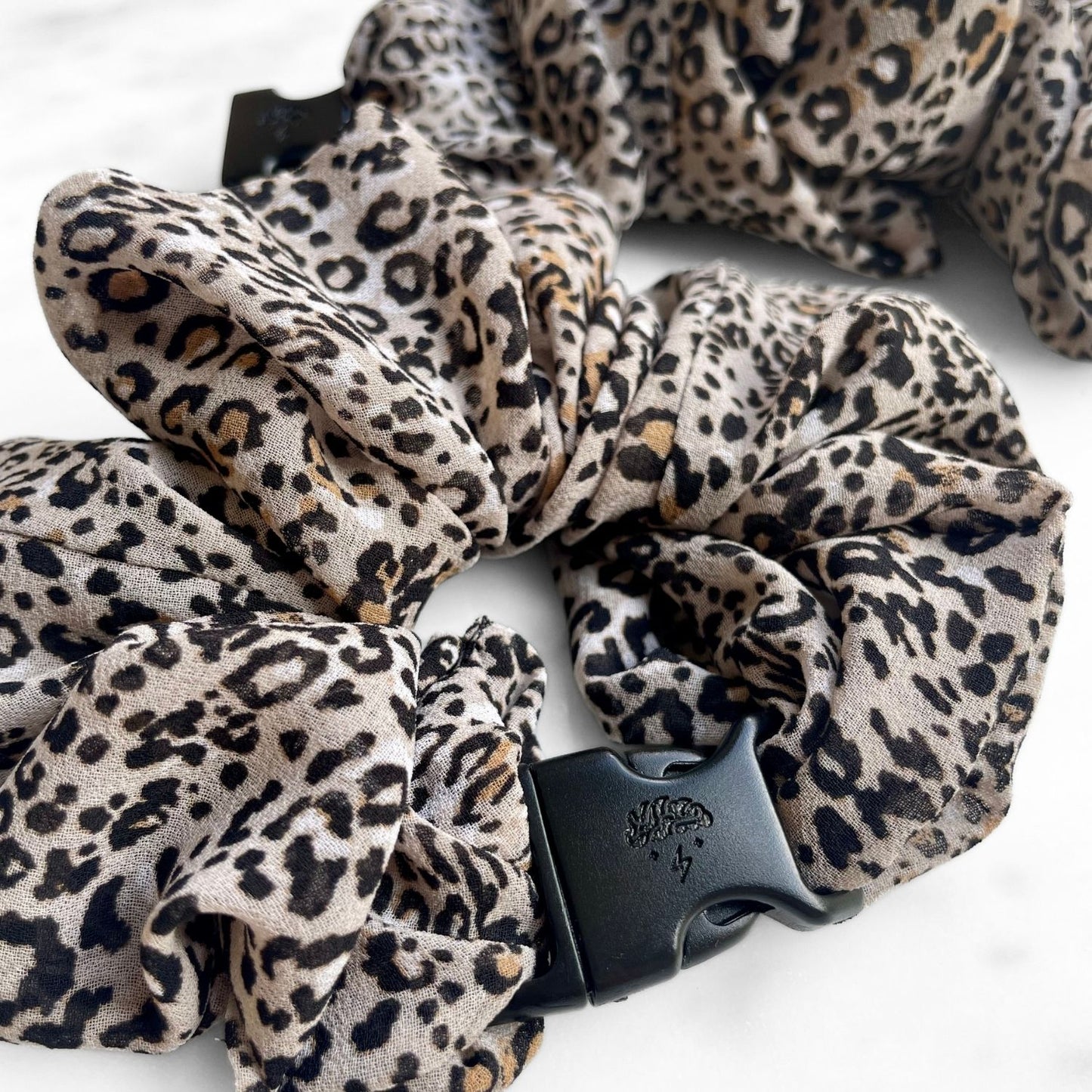 Close view of the leopard print chiffon and navy buckle on a Buckle Scrunchie