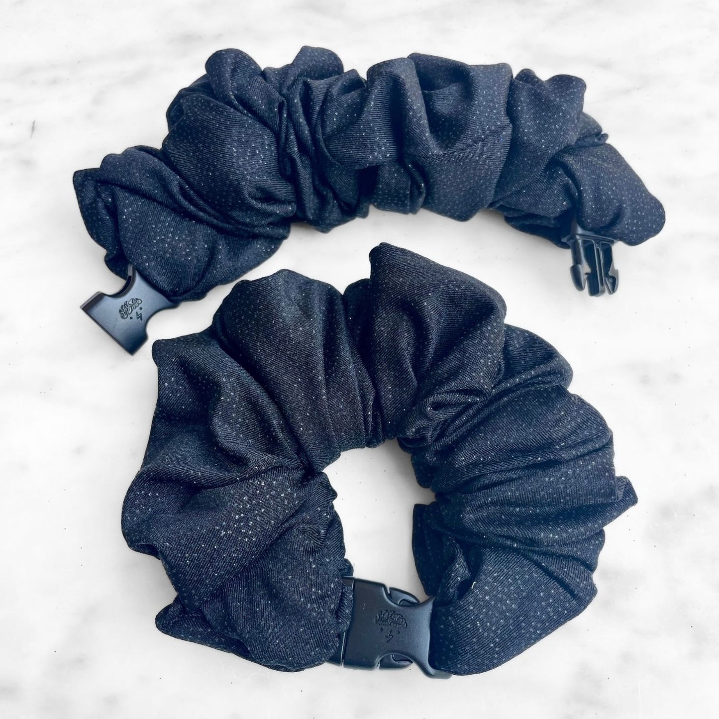 Black glitter Buckle Scrunchie with a quick-release buckle on marble