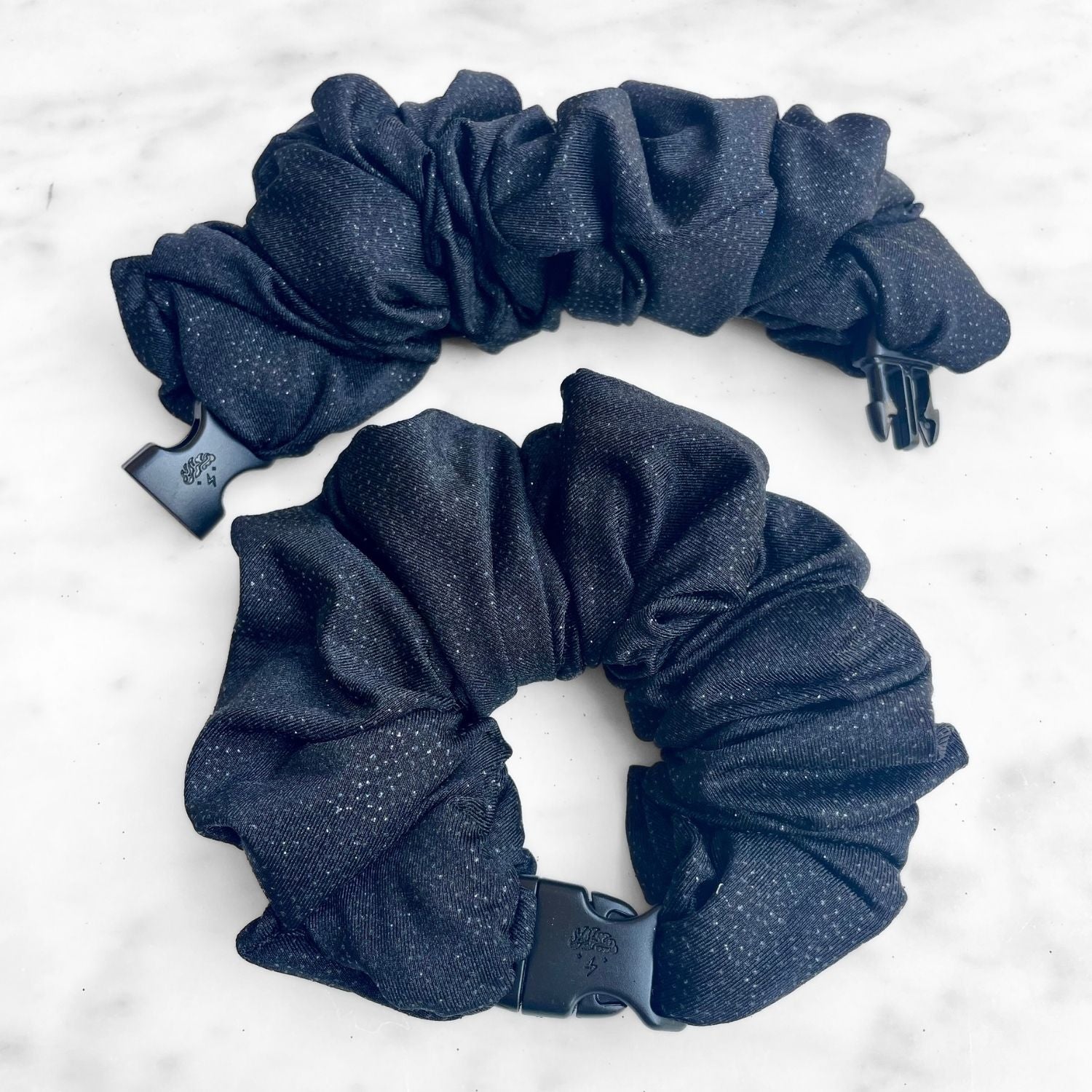Black glitter Buckle Scrunchie with a quick-release buckle on marble