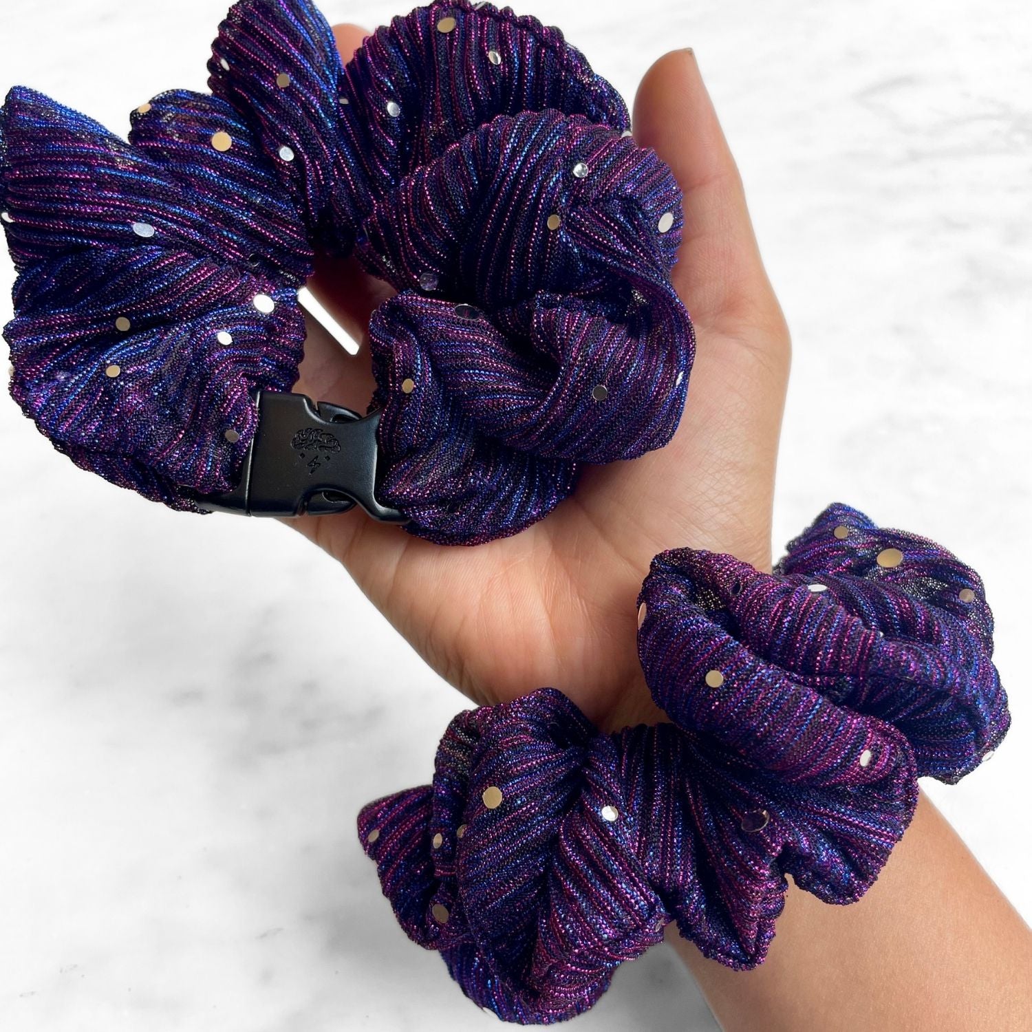 Purple sparkle Buckle Scrunchie held in hand with a second worn on the wrist