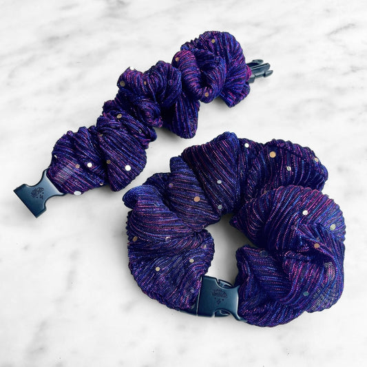 Two purple pleated sparkle Buckle Scrunchies on marble, one unclipped