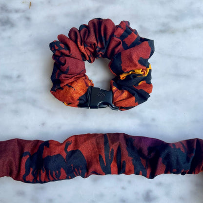 Red and black abstract Buckle Scrunchie above an unclipped one laid flat on marble