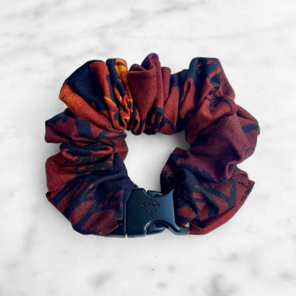 Close view of the dark red and orange abstract print on a Buckle Scrunchie