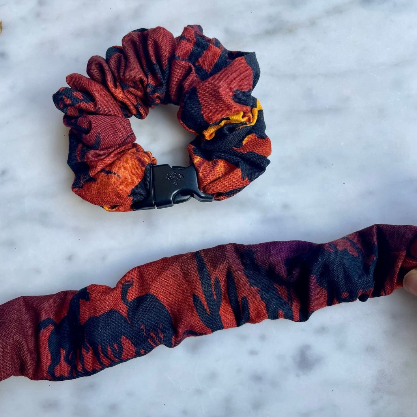 Red and black abstract Buckle Scrunchie beside one opened flat to show its length