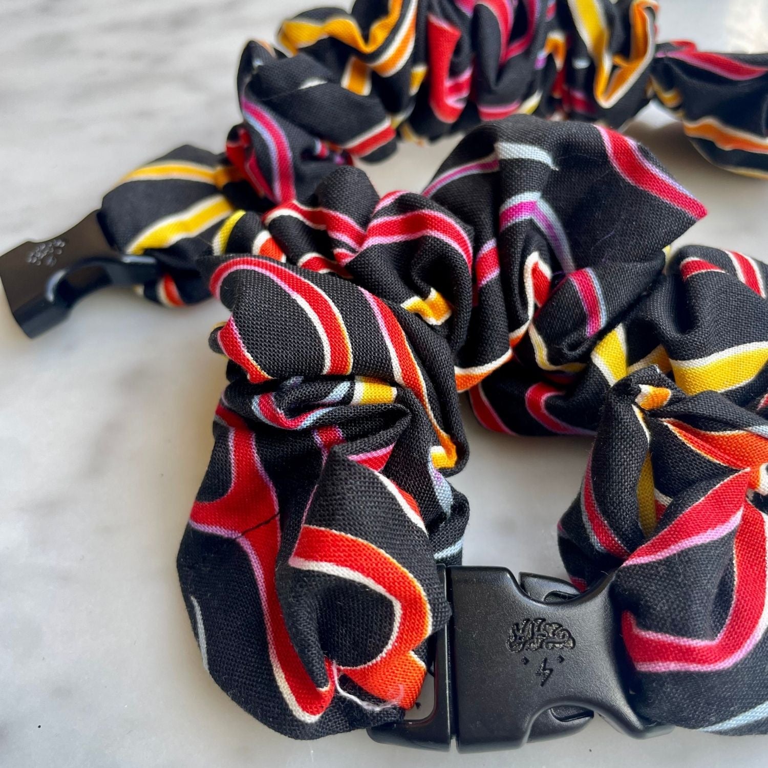 Close view of the red and yellow ribbon swirl print and black buckle