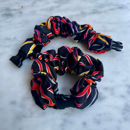 Two black ribbon swirl print Buckle Scrunchies, one open with the buckle unclipped
