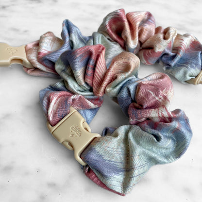 Close view of pink and blue watercolor Buckle Scrunchies with tan quick-release buckles