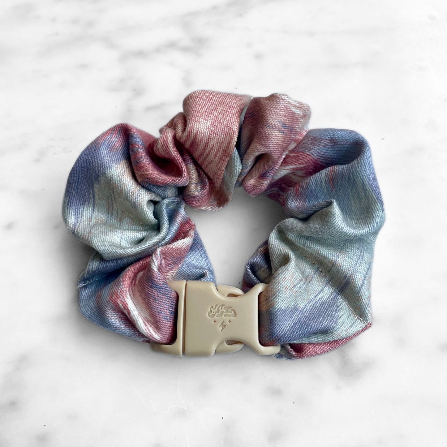 Single pink and blue watercolor Buckle Scrunchie fastened with a tan quick-release buckle