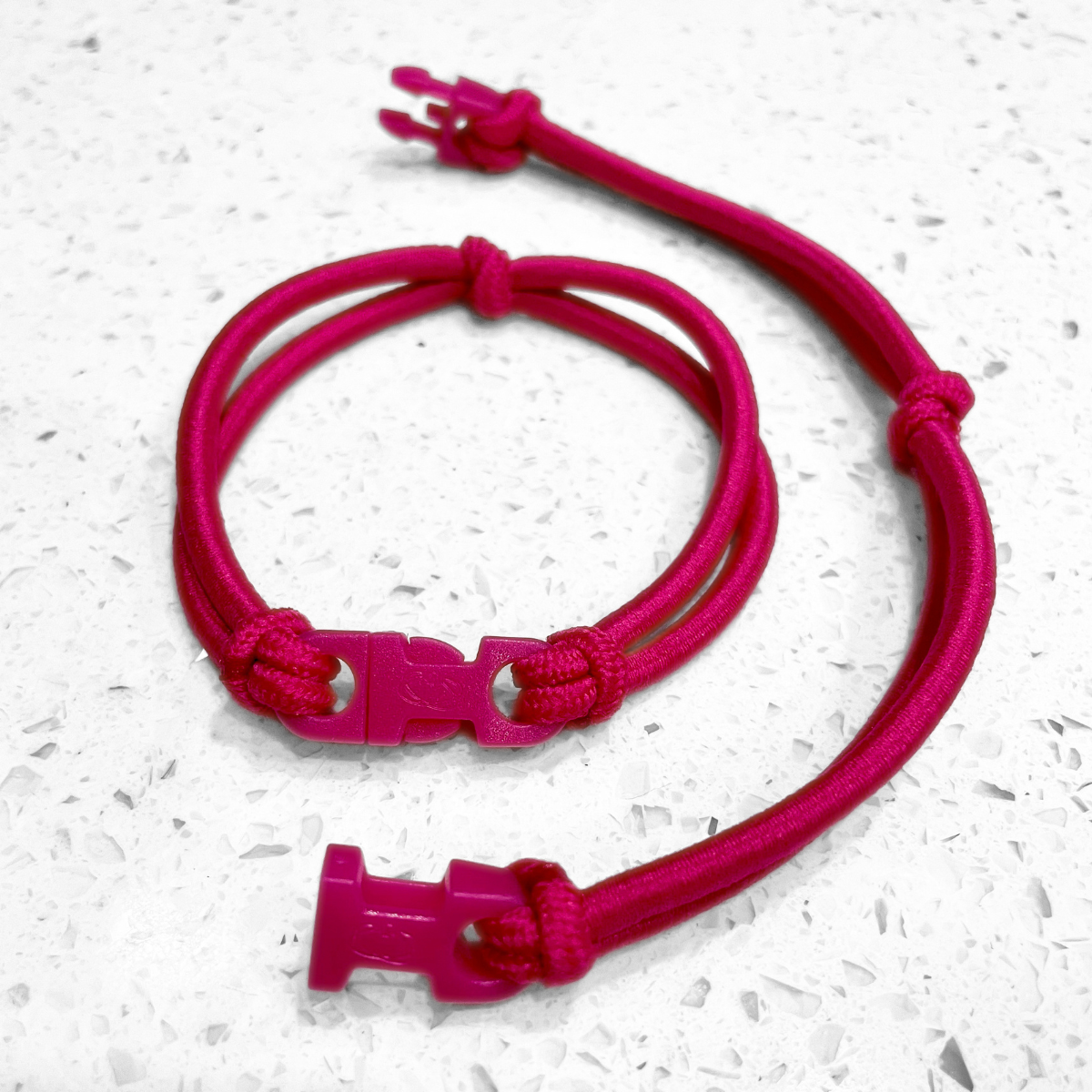 Hot Pink Buckle Hair Tie elastic clasped in a loop beside an open one showing the hot pink quick release buckle